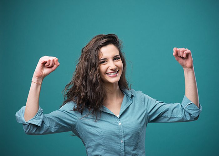 Confident woman smiling with her arms raised in victory