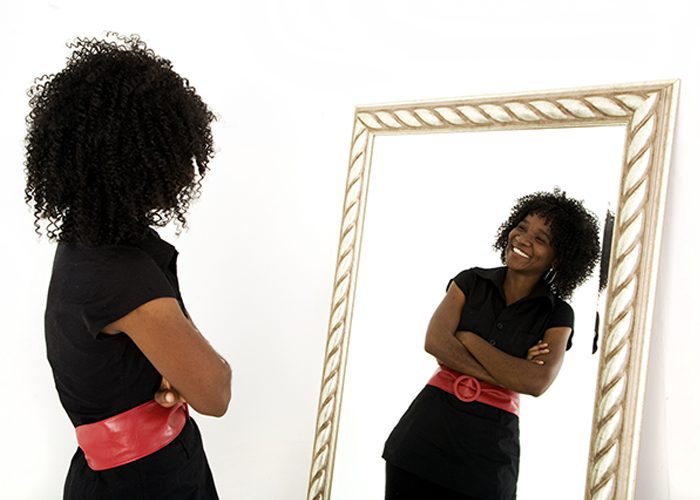 Woman confidently looking at her reflection in the mirror and smiling