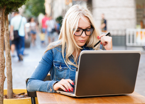 Blonde woman working alone on her laptop at an outdoor desk