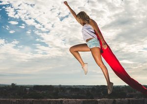 Woman in superwoman pose with a red cape