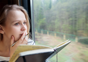 Woman looking pensive with her journal book open on a train