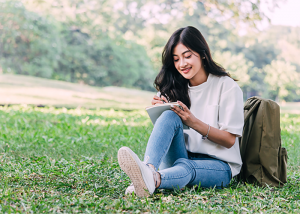 Young woman journaling outdoors on the grass