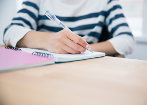 Woman in striped shirt writing into her journal