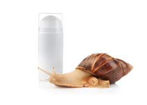 snail next to a white bottle of snail cream