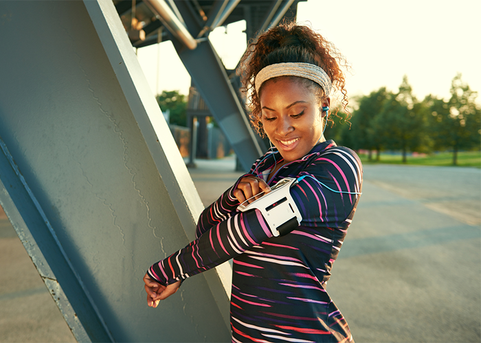 African American woman outdoors setting her workout app for women before a run