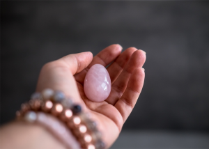 Woman holding a pink yoni egg in her palm