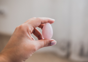 Close up of hand holding a pink yoni egg