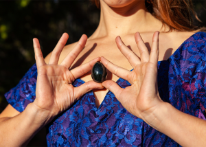 Woman holding a black yoni egg up to her chest
