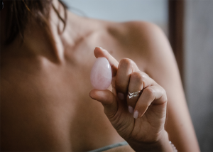 Woman holding a pink yoni egg with her finger and thumb