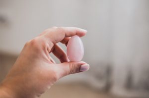woman holding a pink jade yoni egg