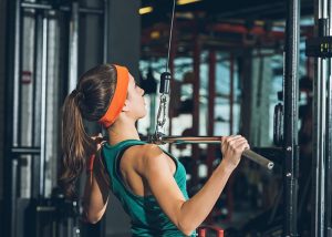 Woman using gym machines for chest and tricep workout