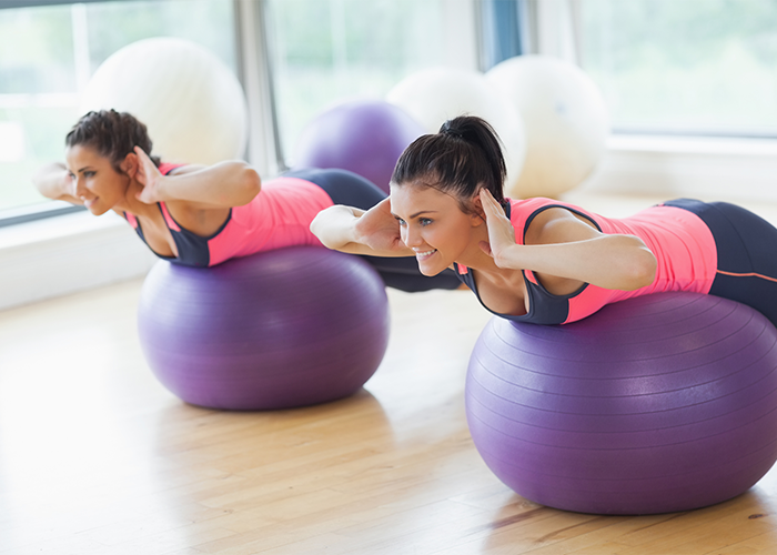 Woman using exercise balls for lower back workouts.