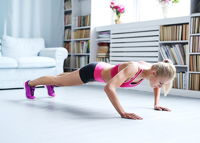 Woman doing push-ups at home as part of a calisthenics workout.