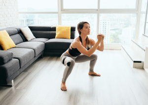 Woman doing squats in a well-lit living room for a calisthenics workout