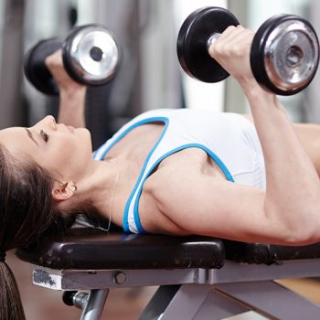 woman using dumbells in chest and tricep workout