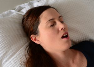 Woman snoring in bed with her mouth open.