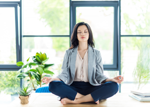 Woman sitting on her office desk doing meditation for stress relief