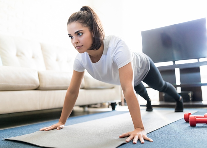 Woman planking in her home as part of a beginner calisthenics workout plan.