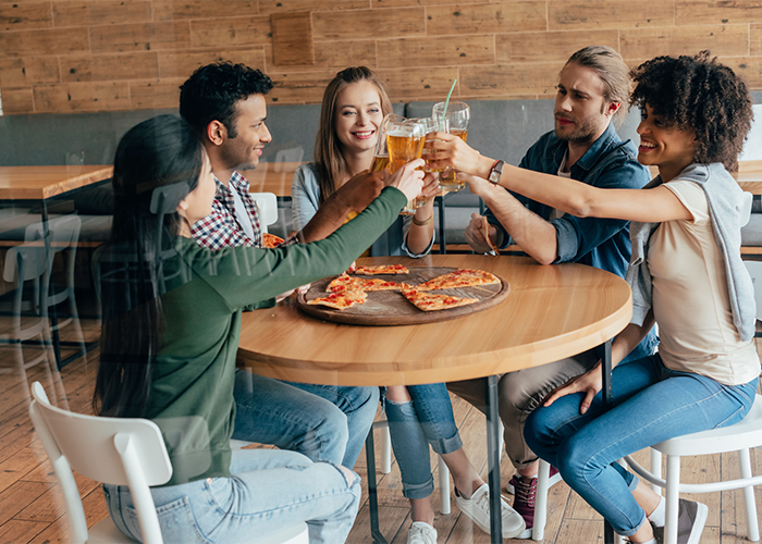 Group of friends in a restaurant having drinks and a pizza