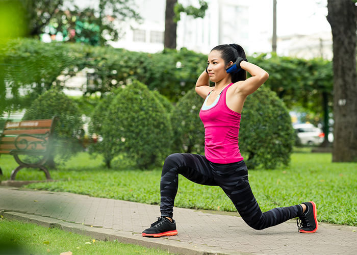 Woman doing lunch and crunch balance exercises in a park