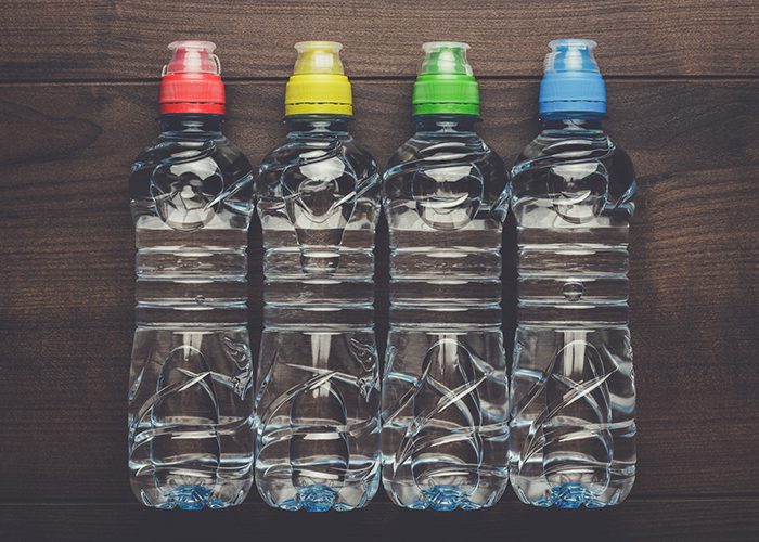 Four bottles of water with different colored caps