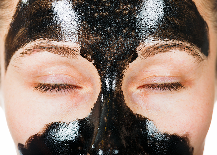 Woman with a black facial mask to remove blackheads from problem areas