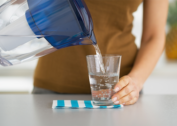 Woman pouring water from a water filter pitcher into a glass