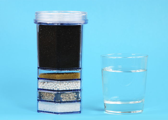 Different layers of carbon filters next to a glass of water