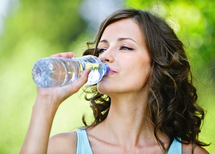 Woman drinking bottled water outdoors