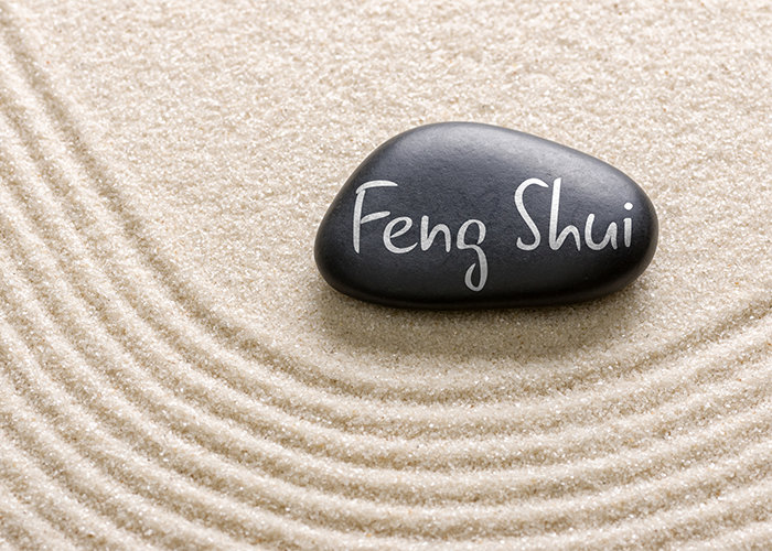 Feng shui written on a black pebble laying on white sand