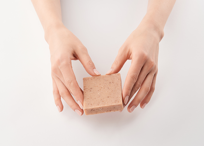 Female hands holding a bar of goat milk soap around the edges