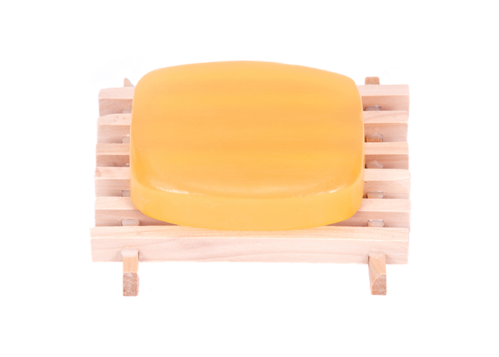 A bar of homemade goat milk soap on a wooden soap dish