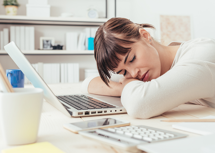 Woman napping in front of her laptop at work