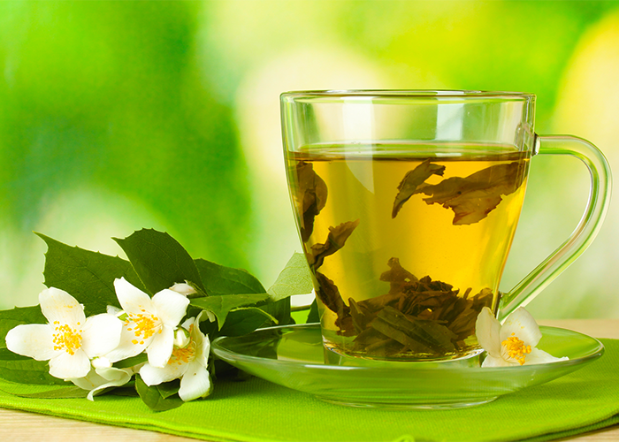 Jasmine tea in a transparent teacup against a green background