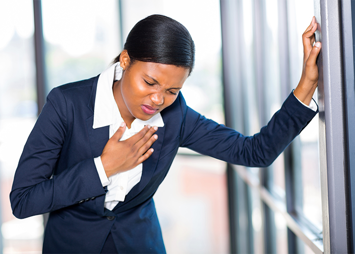 Woman in formal office suite holding her chest in pain