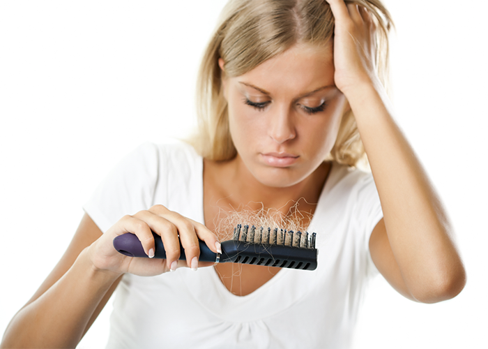 Woman with hair loss looking at her hairbrush with lots of hair in it