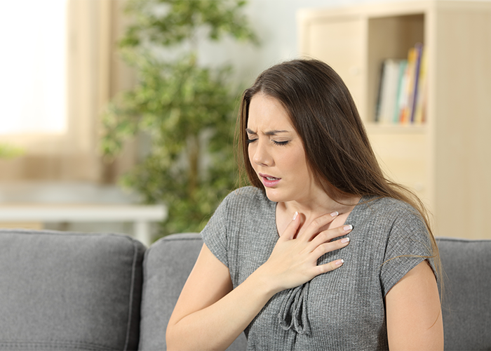 Woman holding her chest because of trouble breathing