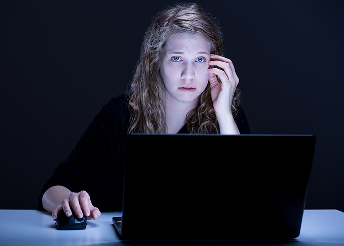 woman in the dark with her laptop looking depressed and lonely