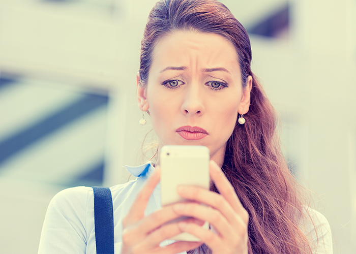 woman looking at her phone with a worried look