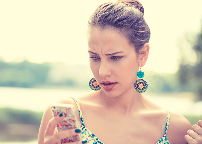 woman looking at her phone in frustration