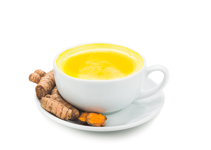 Turmeric tea in a white cup on a white saucer with turmeric root on the side