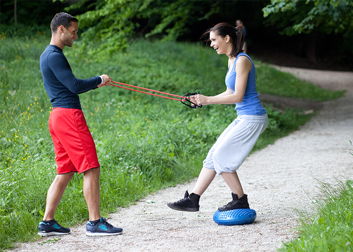 Woman working with a male coach in the park on balance exercises