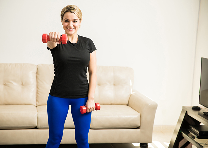 Woman doing shoulder exercises at home with dumbbell