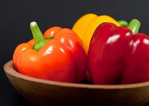 Red, yellow, and orange bell peppers in a bowl