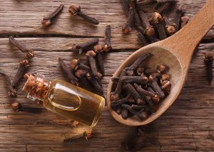 A bottle of clove essential oil surrounded by cloves