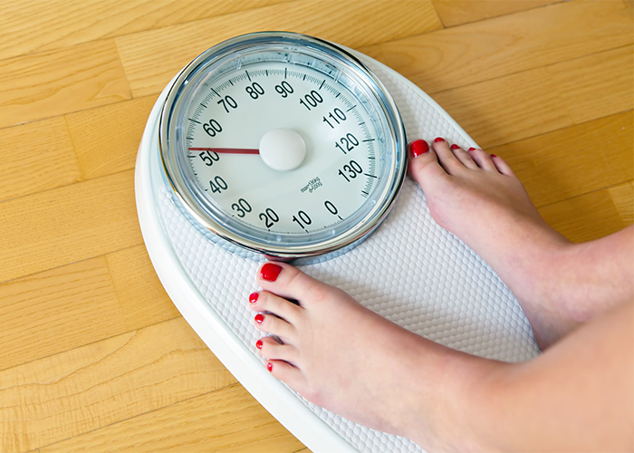 Woman standing on a scale to check her weight loss due to ketosis