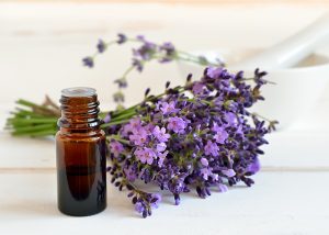 A bottle of lavender essential oil for healthier skin next to fresh sprigs of lavender