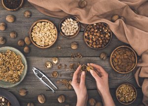 Table filled with bowls of nuts, with a woman cracking a walnut open