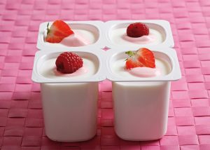 Four punnets of vanilla yogurt topped with fresh strawberries and raspberries
