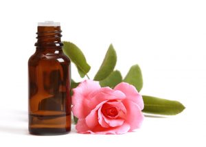 Bottle of anise essential oil blended with rose essential oil next to a fresh rose stem